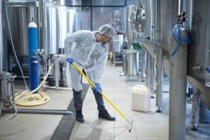 An industrial cleaner mopping the floor to remove stains, dirt, and oils in their production area.