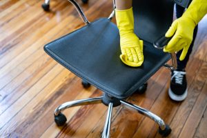 A man is wiping a chair, demonstrating how to clean an office chair to maintain its appearance and durability.