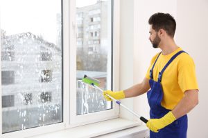 A professional cleaner demonstrates the benefits of regular window cleaning for businesses during the winter season.