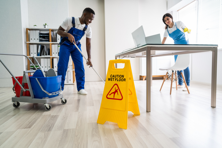 Two professional cleaners in blue uniforms mopping a tile floor, a standard service featured on a comprehensive cleaning business checklist.