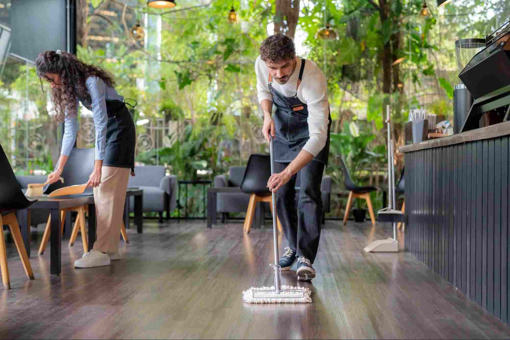 Restaurant staff deep clean laminate floors with a microfiber mop to maintain a clean and well-kept commercial space.