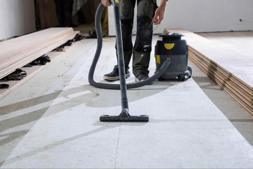 Worker vacuuming construction dust from the floor during post construction cleaning.