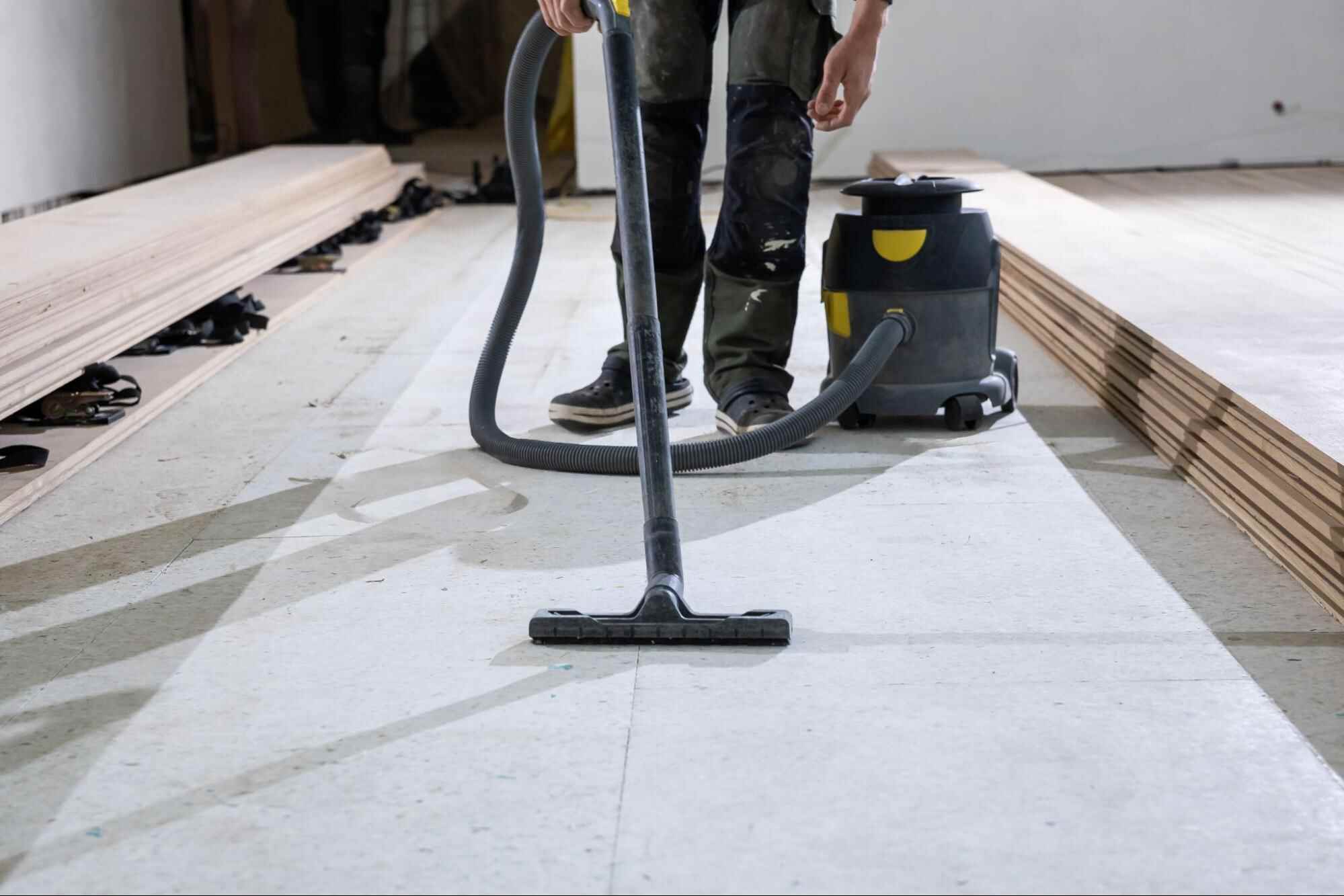 Worker vacuuming construction dust from the floor during post construction cleaning.